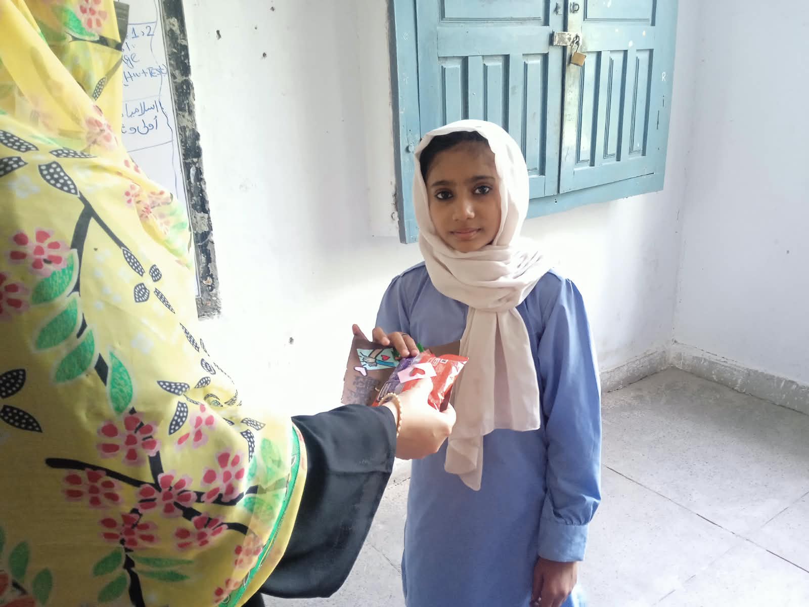Meerab distributing packages to young girls in her community