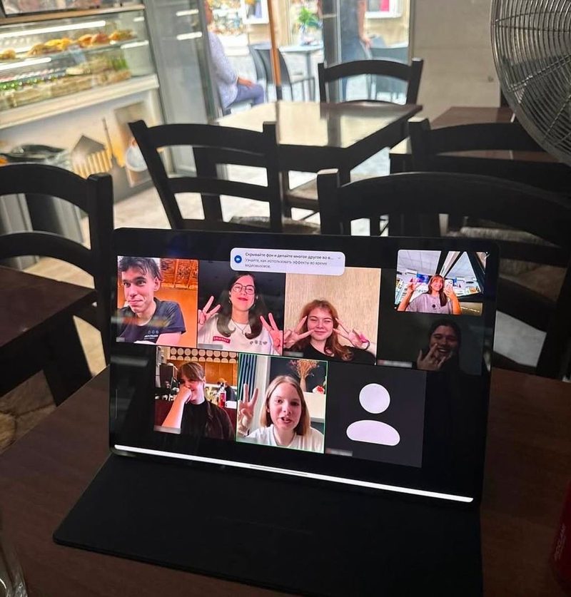 A laptop on a table showing a video call with several participants