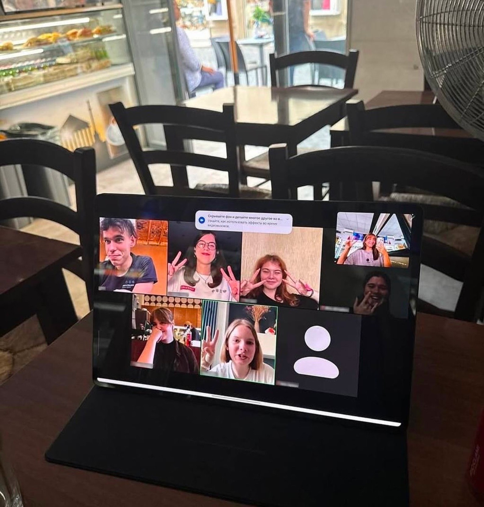 A laptop on a table showing a video call with several participants